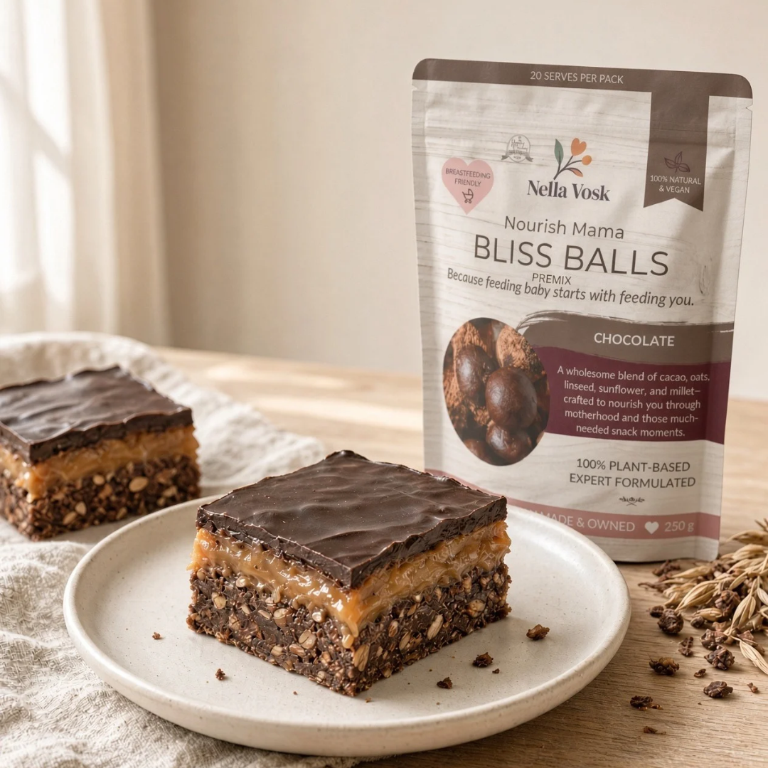 Healthy no bake caramel slice cut into squares showing the oat base, golden caramel and dark chocolate layers on a timber board, Nella Vosk