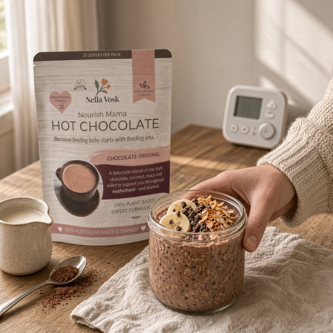 Chocolate overnight oats in a glass jar topped with sliced banana, cacao nibs and coconut flakes, with a pack of Nourish Mama Lactation Hot Chocolate, Nella Vosk